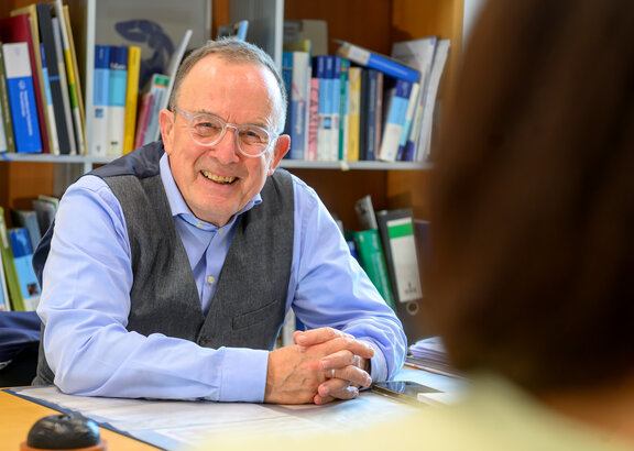 Dr. med. Christoph Kruse führt ein Gespräch mit einer Patientin und schaut dabei in die Kamera und lächelt.