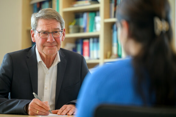 Dr. med. Peter Asmus führt ein Gespräch mit einer Patientin und schaut dabei in die Kamera.